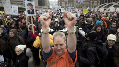 A demonstrator wears handcuffs while protesting on a national day of action against Bill C-51, the government's proposed anti-terrorism legislation, in Toronto on Saturday, March 14, 2015. THE CANADIAN PRESS/Darren Calabrese